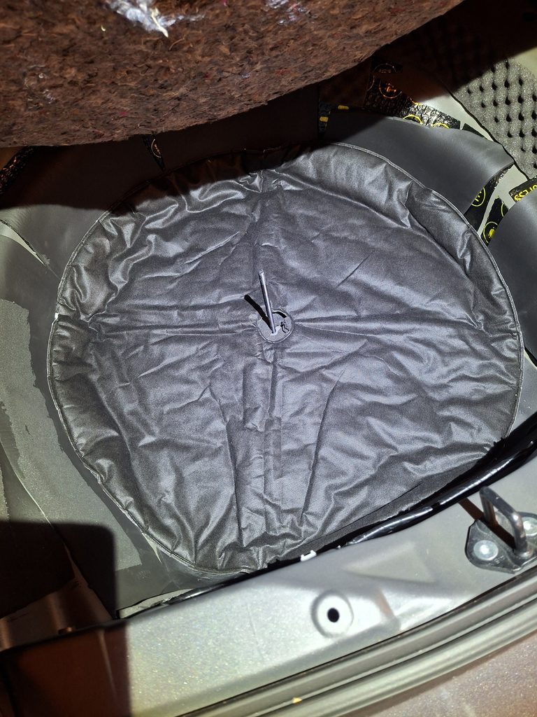Round foam soundproofing pad installed in Toyota Corolla spare wheel well